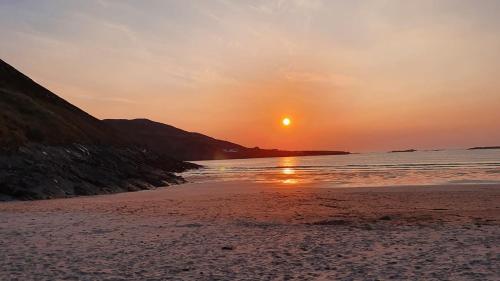 a sunset on a beach with the sun setting at Blue Pearl Apartment in Downings