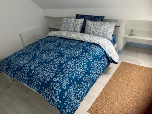 a bed with a blue and white comforter and pillows at Blue Pearl Apartment in Downings