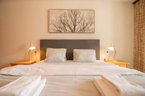 アローザにあるBrüggli A24 by Arosa Holidayのベッドルーム(白い大型ベッド、ランプ2つ付)