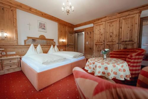 a bedroom with a bed and a table and chairs at Dandler - Zimmer und Ferienwohnungen in Fieberbrunn