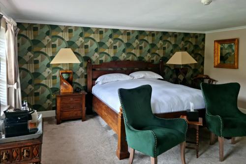 a bedroom with a bed and two green chairs at The Ollerod in Beaminster