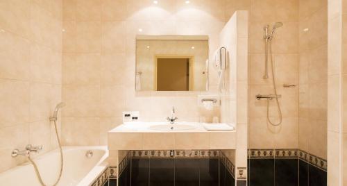 een badkamer met een wastafel, een douche en een bad bij Hotel Restaurant Talens Coevorden in Coevorden