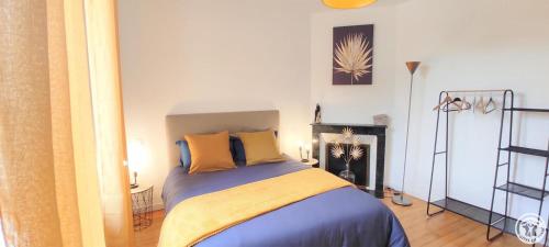 1 dormitorio con cama con sábanas amarillas y chimenea en AU FIL DE L'EAU, en Milly-sur-Thérain