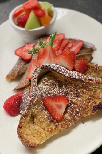 a plate of french toast with strawberries and a bowl of fruit at Leslie Hotel Ocean Drive in Miami Beach