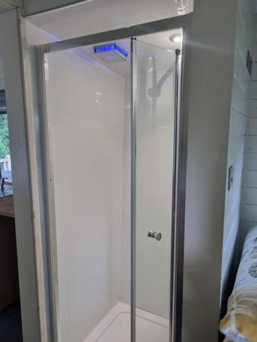 a shower with a glass door in a room at Glamping Hut - Riverview 5 in Garthbeibio