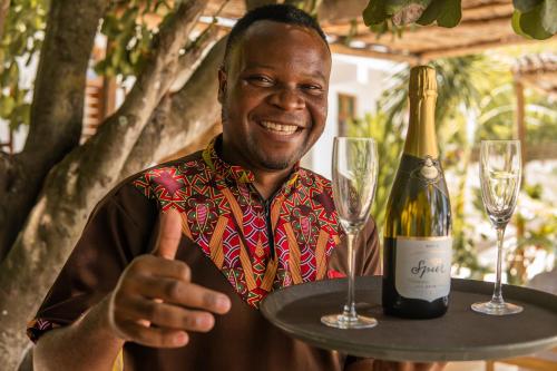 a man giving a thumbs up with a bottle of wine at CoCo Tree House @ Kima Zanzibar, Unique stay in Bwejuu