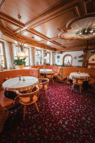 a restaurant with tables and chairs in a room at Dandler - Zimmer und Ferienwohnungen in Fieberbrunn