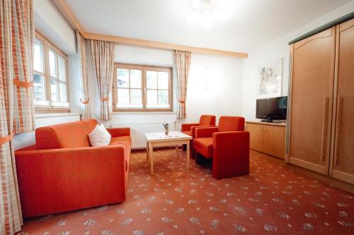 a living room with two red chairs and a television at Dandler - Zimmer und Ferienwohnungen in Fieberbrunn