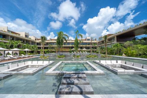 een resort zwembad met een resort op de achtergrond bij MISTIQ Tulum Luxury Apartments in Tulum