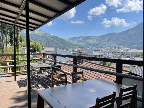 a balcony with a table and chairs and mountains at 旅館 竹屋 Takeya in Yufuin