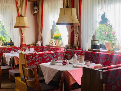 Tannerhof Bed & Breakfast في Caines: غرفة طعام مع طاولتين ومقصورات حمراء