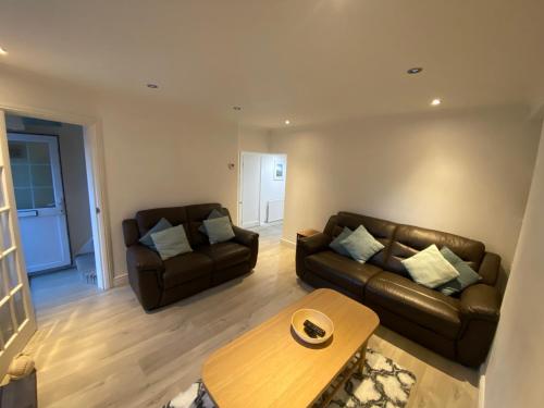 a living room with two leather couches and a coffee table at Sands Reach, dog friendly Tenby house in Tenby