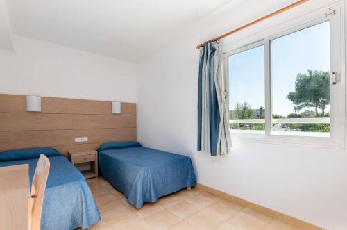 een kamer met 2 bedden en een raam bij Mariner Club in Port d'Alcudia