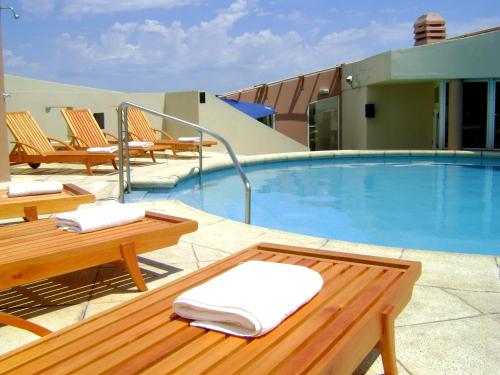 einen Pool mit Stühlen, einem Tisch und einer Bank in der Unterkunft InterTower Hotel in Santa Fe