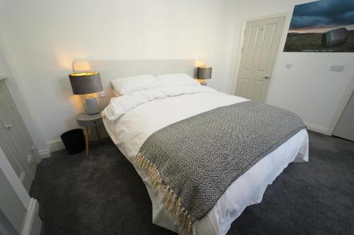 uma cama grande num quarto com 2 candeeiros e um sidx da cama em Immaculate 1-Bed Apartment in Merthyr Tydfil em Merthyr Tydfil