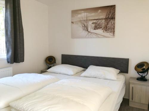 two beds in a bedroom with white sheets at Chalet 516 op Recreatiepark De Wielen in Sint Maarten
