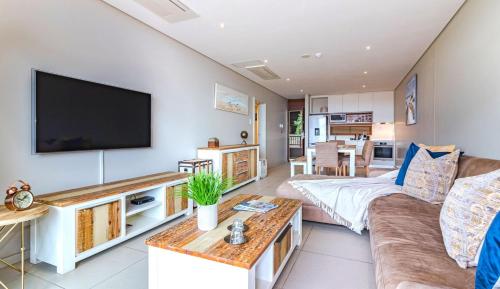 uma sala de estar com um sofá e uma televisão de ecrã plano em Suite 501, Zimbali Suites em Ballito