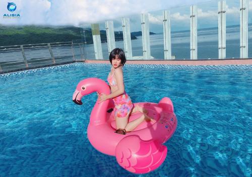 une jeune fille qui roule sur un cygne rose dans une piscine dans l'établissement Alisia Beach Hotel Da Nang, à Đà Nẵng