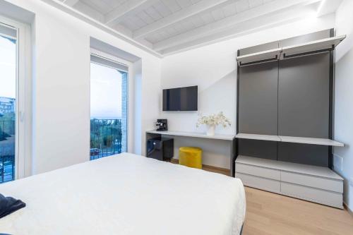 1 dormitorio con 1 cama blanca y TV en Le Dimore en Ortona