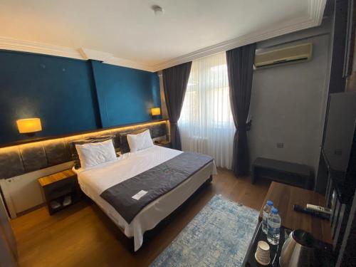 a bedroom with a bed and a blue wall at Rhisos Gold Otel in Rize