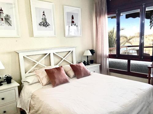 Un dormitorio con una cama blanca con almohadas y una ventana en Primera Linea de Playa con vistas al Mar en Águilas
