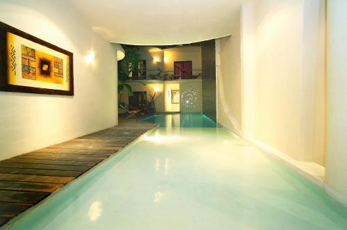 a swimming pool in a house with a wooden floor at Kinbe Hotel Boutique in Playa del Carmen