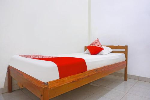 ein Holzbett mit roten und weißen Kissen darauf in der Unterkunft SPOT ON 91786 Kilana Homestay in Makassar