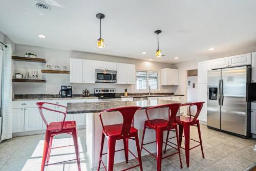 a kitchen with red chairs and a counter with a refrigerator at The Wendover - Entire Home near Lake Michigan! in Norton Shores