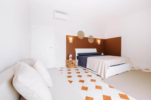 a white bedroom with two beds and a couch at Dimore Dalle Zie in Alberobello