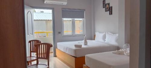 1 dormitorio con 2 camas, 1 silla y 2 ventanas en MOSHIS NEST, en Madurai