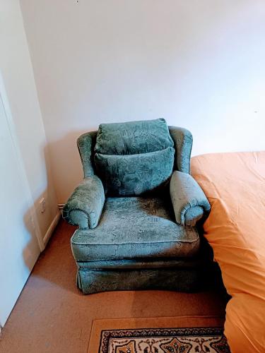 a green chair sitting in a room next to a bed at London Double Room with free parking and wifi in Hornchurch