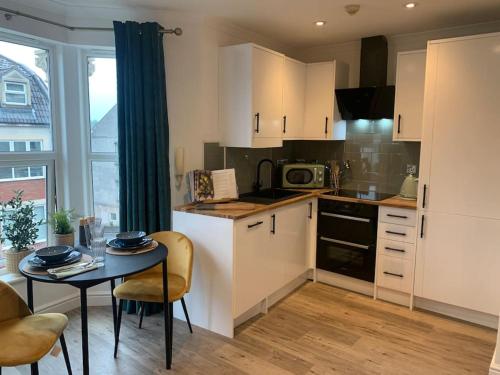 une cuisine avec des placards blancs et une table avec des chaises dans l'établissement Alto - Lovely 2 Bedroom Serviced Apartment Bristol by Mint Stays, à Bristol