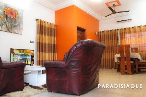 uma sala de estar com uma cadeira de couro e paredes cor-de-laranja em PARADISIAQUE em Cotonou