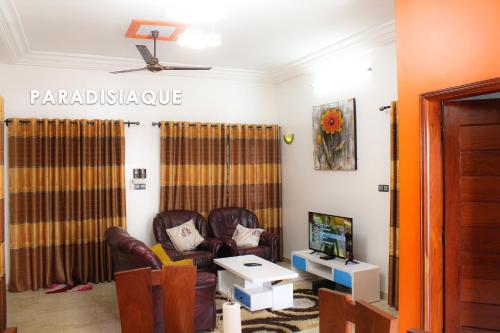 uma sala de estar com uma cadeira de couro e uma televisão em PARADISIAQUE em Cotonou