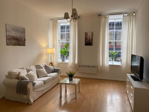 a living room with a couch and a tv at Lovely 1-Bed Apartment in Glasgow Merchant City in Glasgow