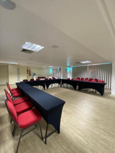 a conference room with a long table and red chairs at Nobile Suítes Tambaú in João Pessoa