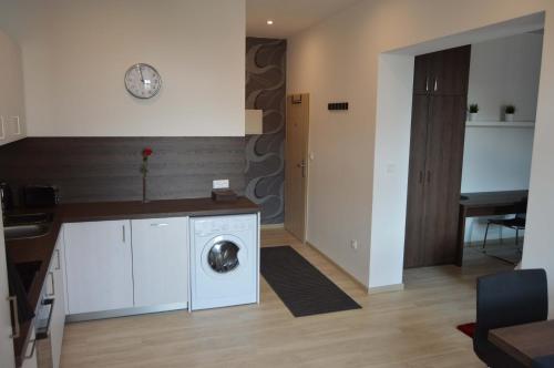 a laundry room with a washing machine and a clock on the wall at Atrium Apartments in Brno