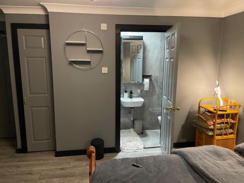 a bedroom with a bathroom with a sink and a mirror at Da Vinci Guest House & Guest Parking, A Real Gem in Crawley
