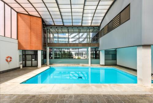 a swimming pool in a building with a ceiling at Micampus Estanislao del Campo, Student Residence in Seville