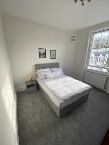 a white bedroom with a bed and two windows at Spacious 2 Bedroom flat in Paddington in London
