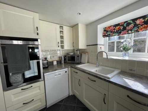 a kitchen with white cabinets and a sink and a window at Selwood Cottage Annex in Frome