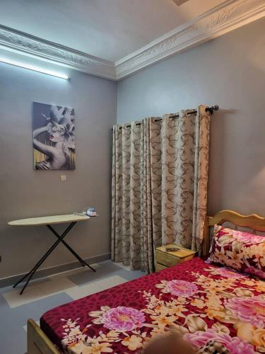- une chambre avec un lit, une table et des rideaux dans l'établissement MERRY LAND, à Cotonou