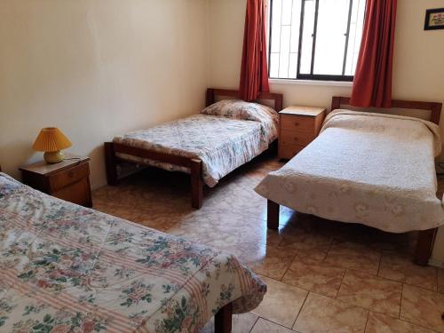 Cette chambre comprend 2 lits et une fenêtre. dans l'établissement Linda casa con piscina en el quisco., à El Quisco