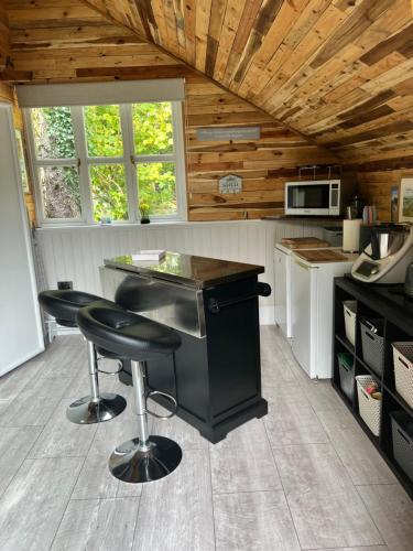 a kitchen with a counter and two stools in it at The Shed . A cosy, peaceful, 96% recycled, chalet. in Swansea