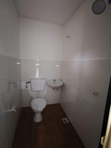 een witte badkamer met een toilet en een wastafel bij SB PRIMA VILLA APRTMENT in Tanah Rata