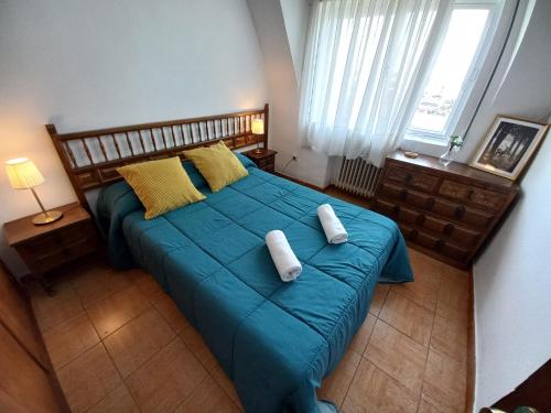 a bedroom with a blue bed with two pillows on it at Casa Rural Alameda con chimenea y jardín in El Barco de Ávila