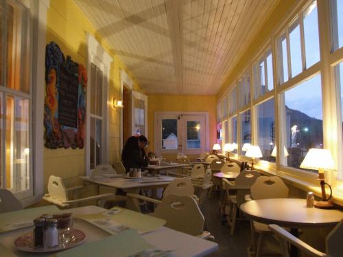 a dining room with tables and chairs and windows at Auberge du Café chez Sam in Baie-Sainte-Catherine