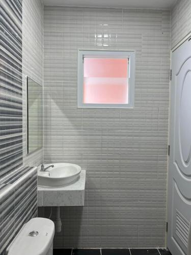 a bathroom with a sink and a toilet and a window at Thana Apartment in Ban Phan Sadet Nai