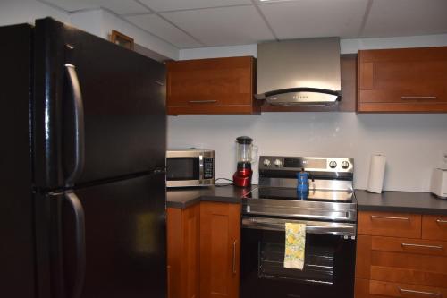 a kitchen with a black refrigerator and wooden cabinets at Cozy Suite with HOT TUB & Highspeed Internet in Grimsby