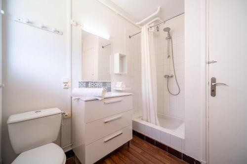 a white bathroom with a shower and a toilet at Jardin accès plage privé - Petit-Fort-Philippe in Gravelines